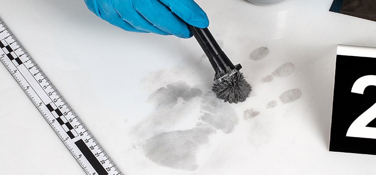 hand print being dusted on white surface with evidence marker 2 and ruler for scale