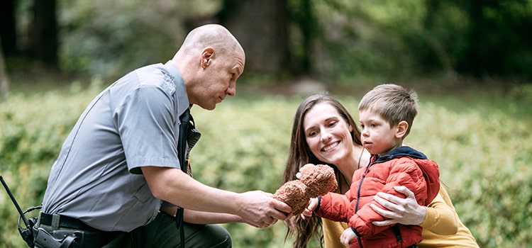 police officer hands teddy bear back to little boy with mom