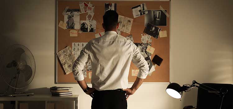male agent stands in front of bulletin board studying case