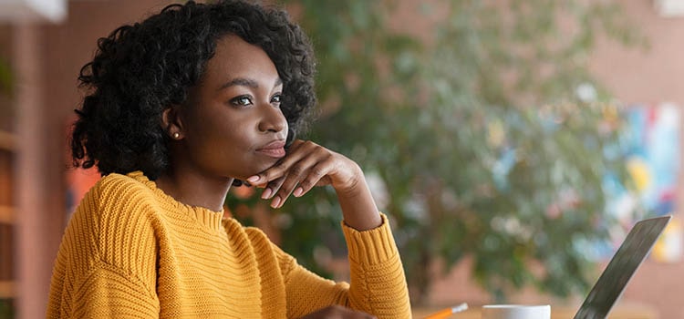 woman in front of laptop stares thoughtfully
