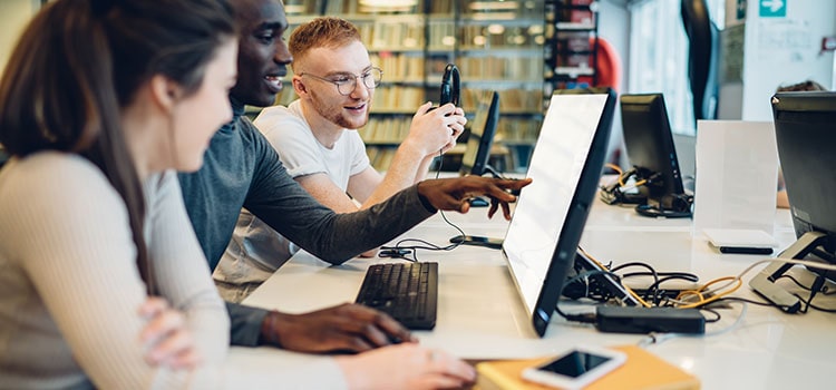 three students collaborate at library computer station