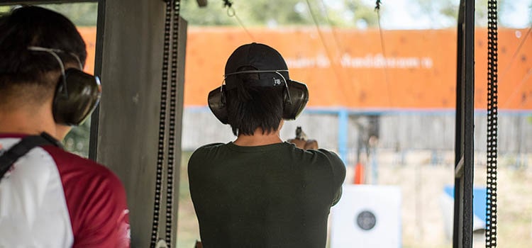 gun range user aims at target as instructor watches