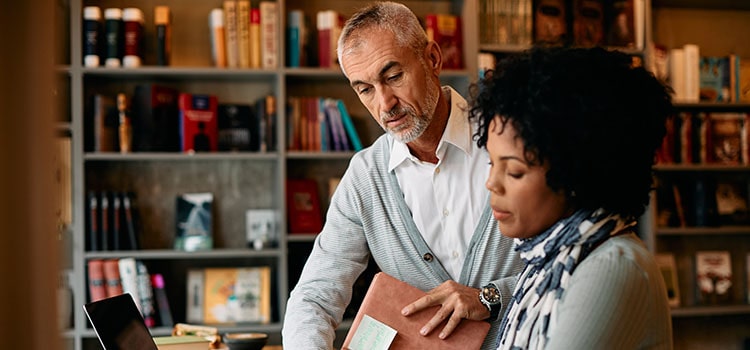 two adults discuss research results in library