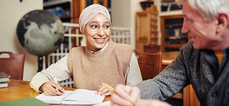 graduate student discusses work with professor at desk
