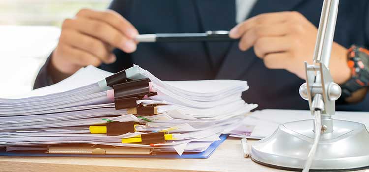 paralegal holding pen ponders stack of case files on desk