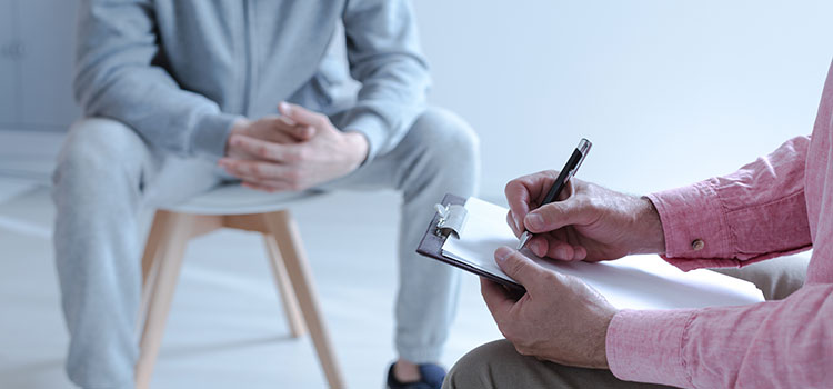 hands interviewing prisoner and taking notes on clipboard