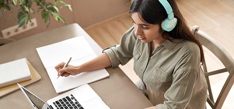 woman with headphones taking the cfe certification exam on laptop