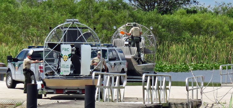 florida state law enforcement officers unload police marked airboats at boat ramp