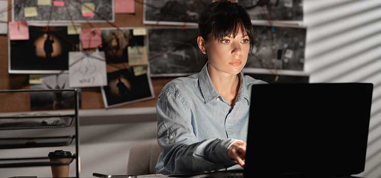woman criminal investigator looking at files on computer