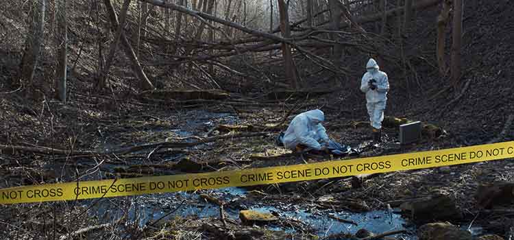 two forensic crime scene investigatoes look in riverbed for clues