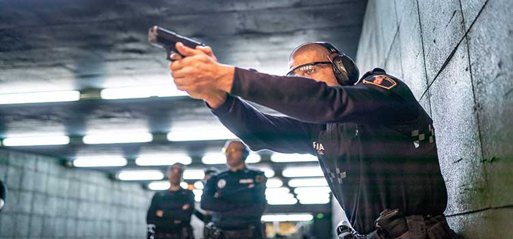 police officer practices with a firearm while two officers watch in background