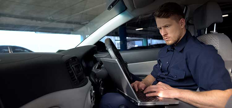 police officer searches on his laptop while sitting in police cruiser