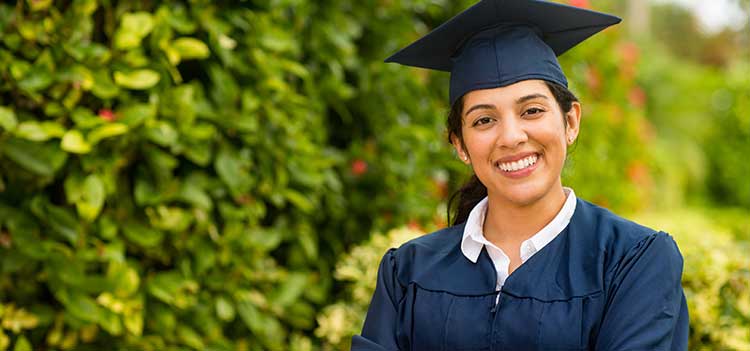 graduate in cap and gown smiles at camera