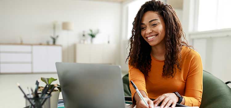woman smiles as she does research on her laptop