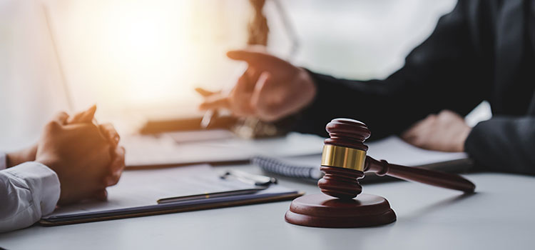 lawyer confers with client as gavel of justice sits on desk