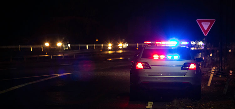 state trooper vehicles with lights on parked by accident scene on dark highway