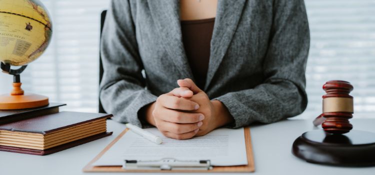 legal professional sits with their hands on their desk next to a gavel
