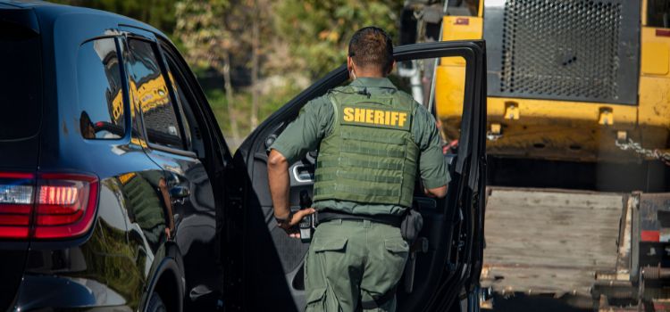 sheriff's deputy wearing bulletproof vest opens the passenger door of a car